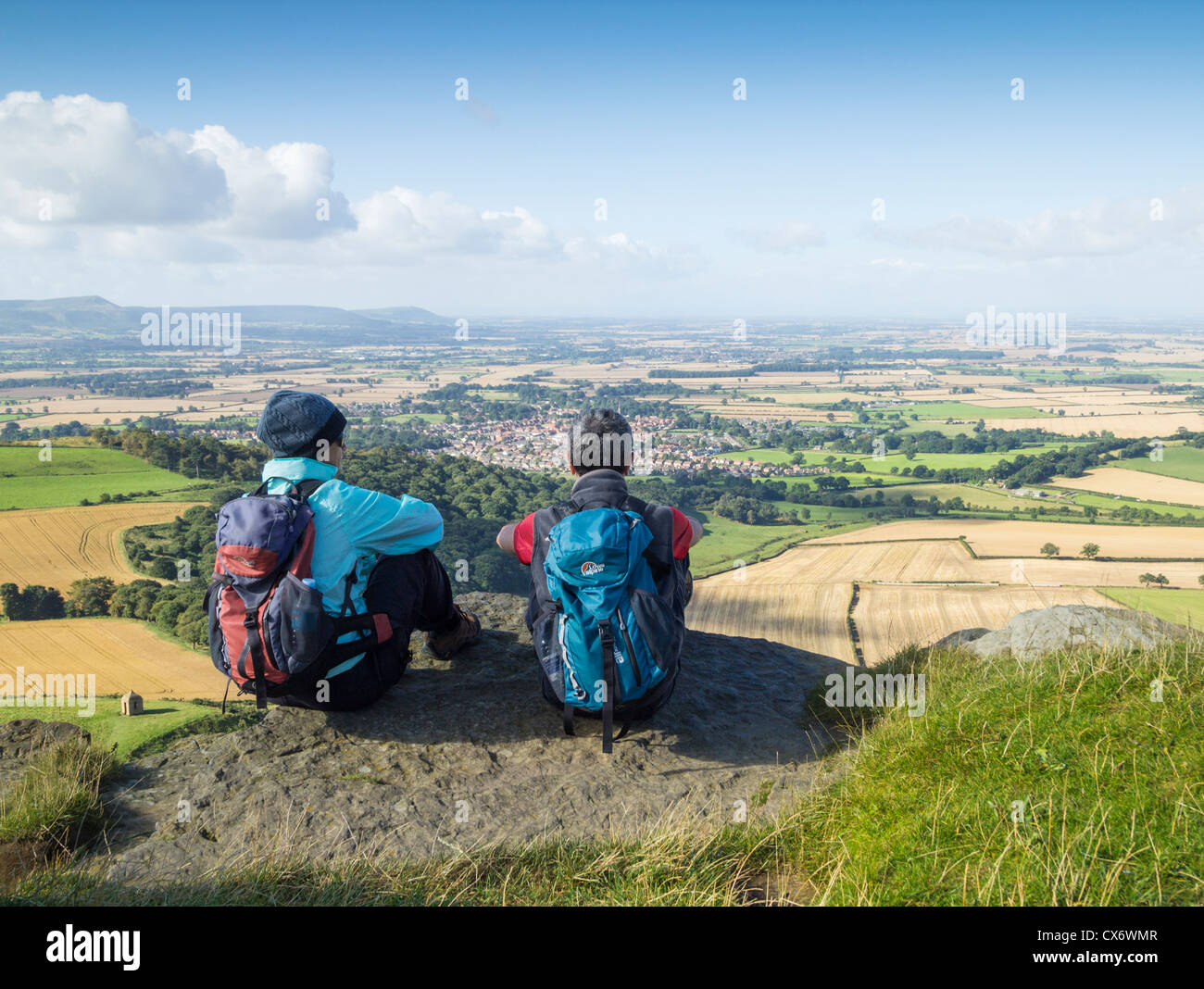Les randonneurs masculins et féminins ovelooking Grande Ayton village de Roseberry Topping haut de près de Great Ayton, Yorkshire du Nord Banque D'Images