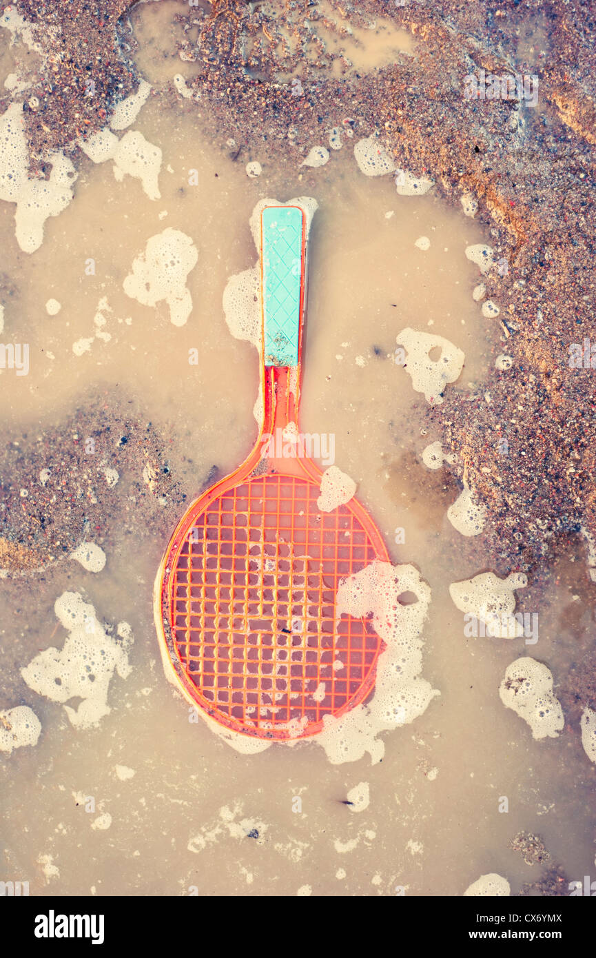 Raquette de tennis jouet en plastique se trouvant dans l'eau flaque Banque D'Images
