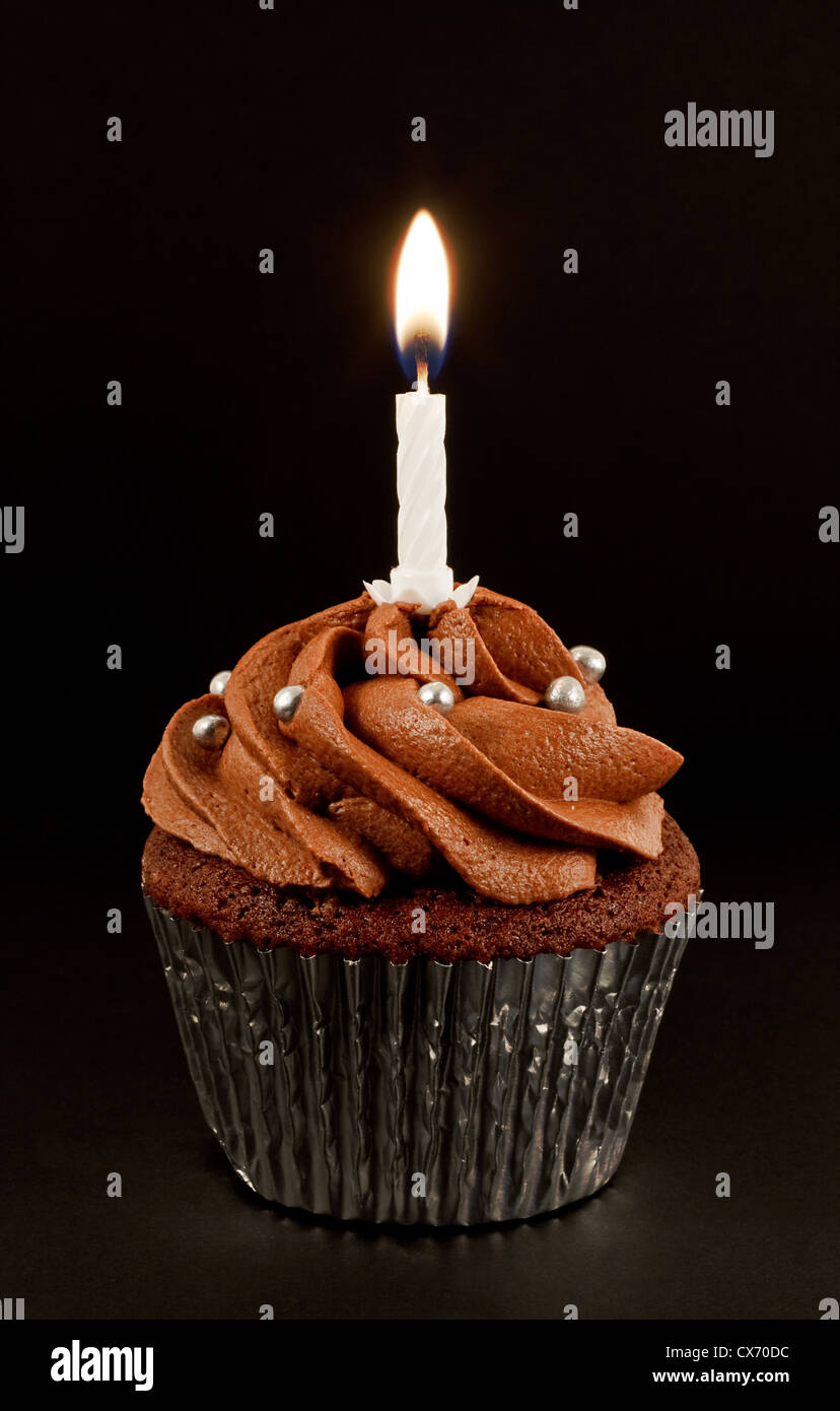 Un chocolat maison cup cake avec une seule bougie allumée pour célébrer un anniversaire ou une autre anniversaire Banque D'Images