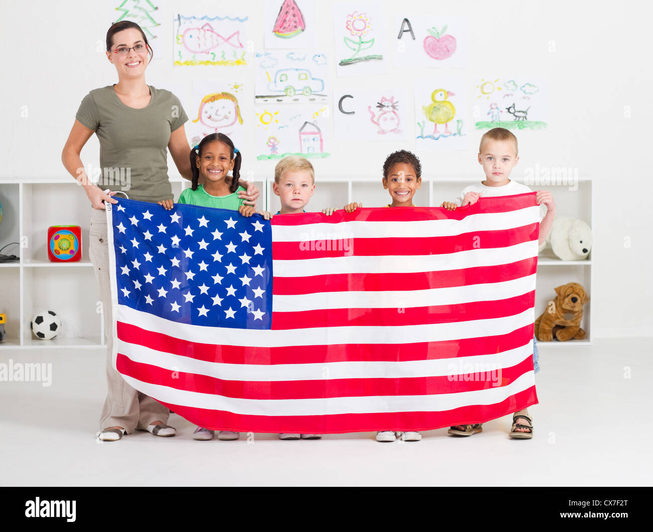 Les élèves de maternelle et professeur américain tenant un drapeau USA Banque D'Images