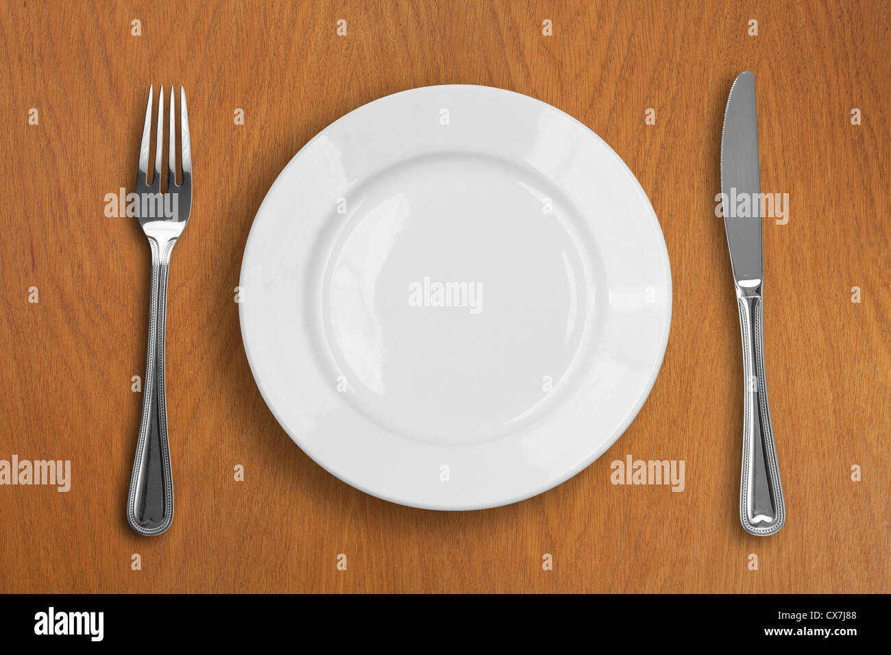 Plaque blanche ronde, couteau et fourchette sur table en bois Banque D'Images