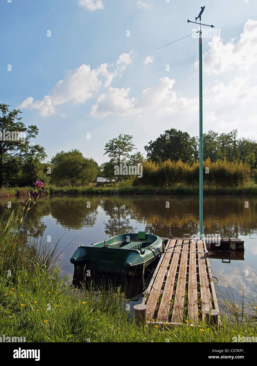 Dock flottant sur un étang avec un petit bateau et une girouette Banque D'Images