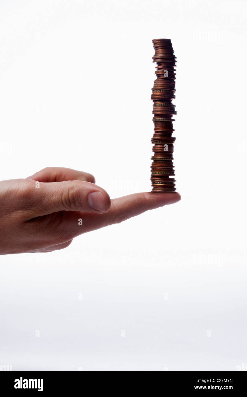 Un doigt humain balance une pile de diverses pièces en euro, close-up Banque D'Images