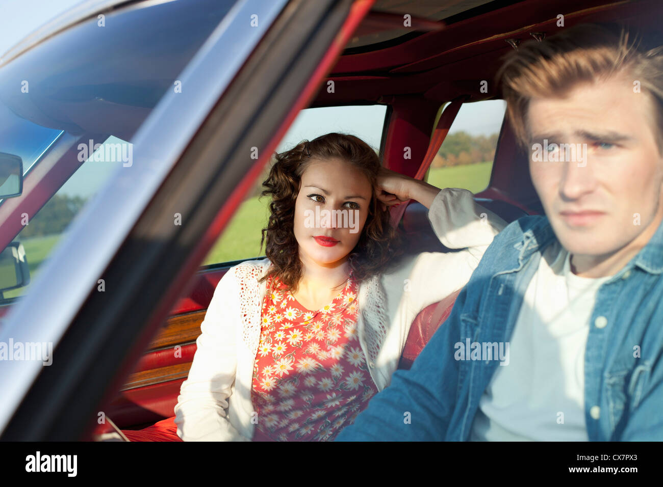 Une jolie fille rockabilly à à son petit ami de l'irritation, en position assise, dans une voiture d'époque Banque D'Images
