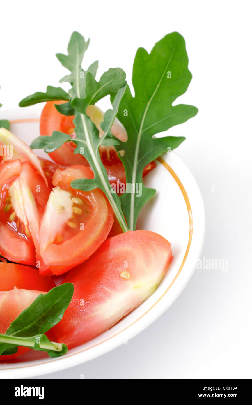 Tomates en salade de roquette dans une tasse blanche, studio isolated Banque D'Images
