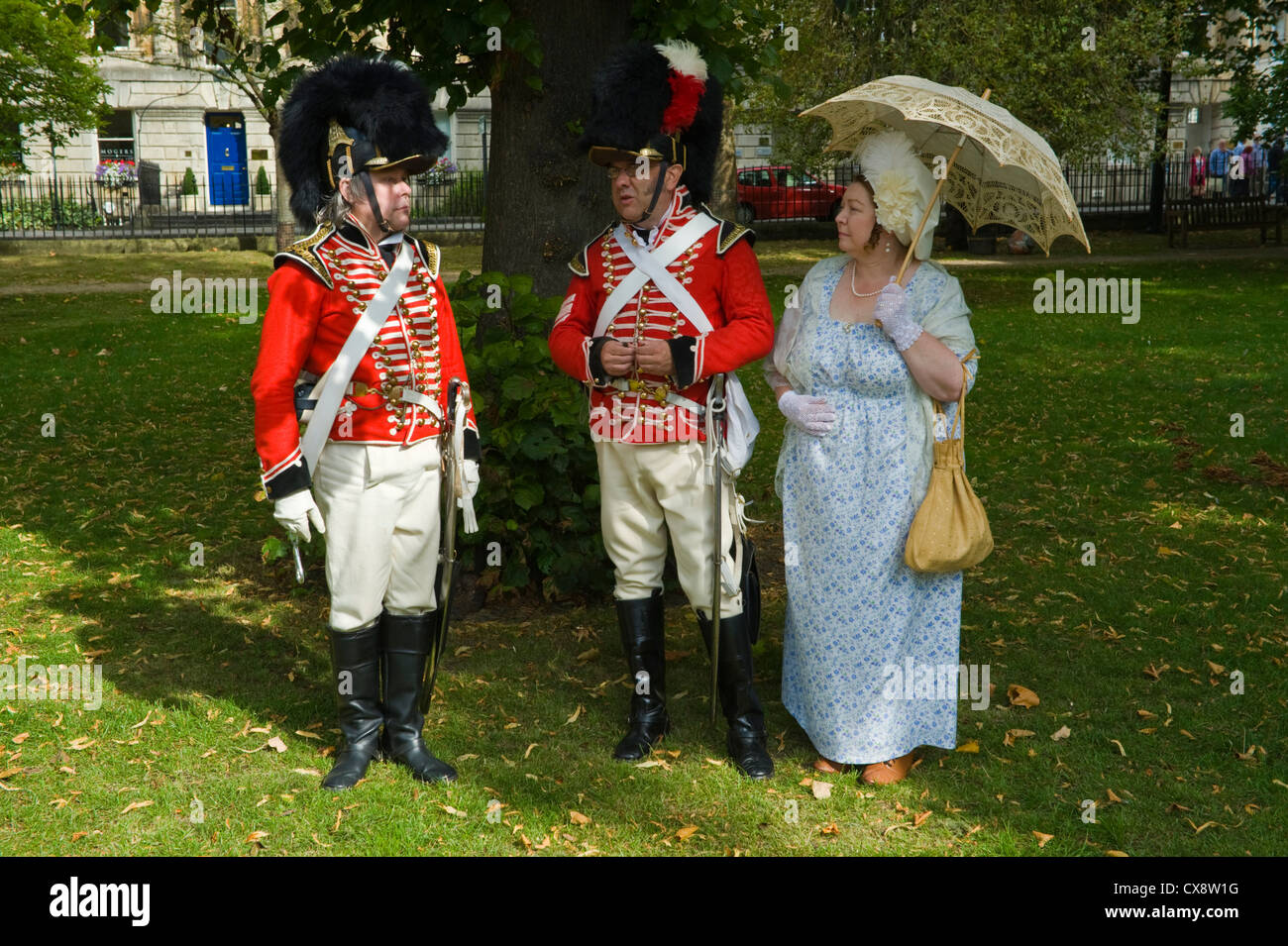 Manteau rouge des soldats en uniforme Regency posent avec dame en costume en parc dans le centre-ville de Bath au début du Festival de Jane Austen Banque D'Images