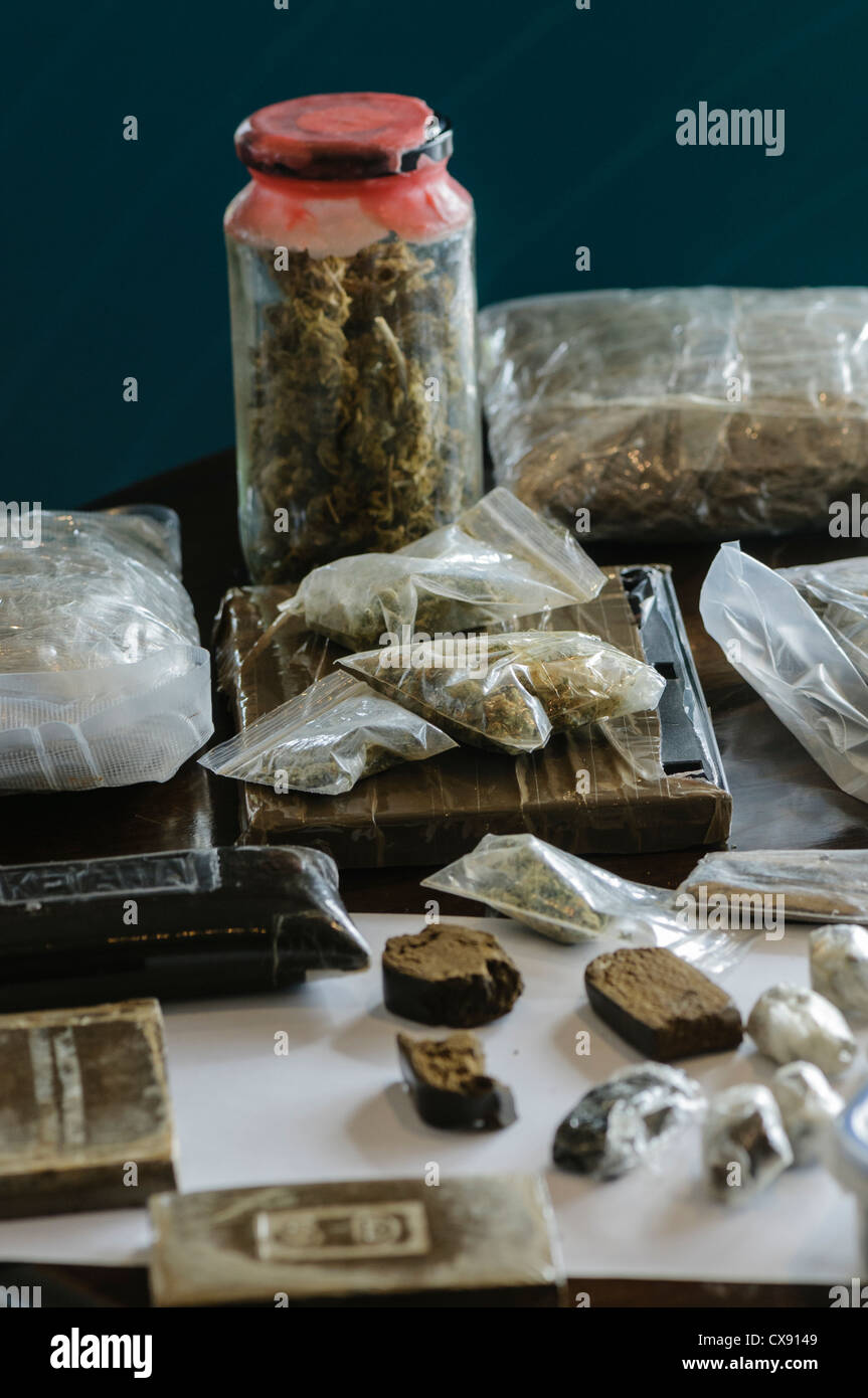 Des blocs/briques de la résine de cannabis avec bols et sacs de feuilles de cannabis sur l'affichage Banque D'Images