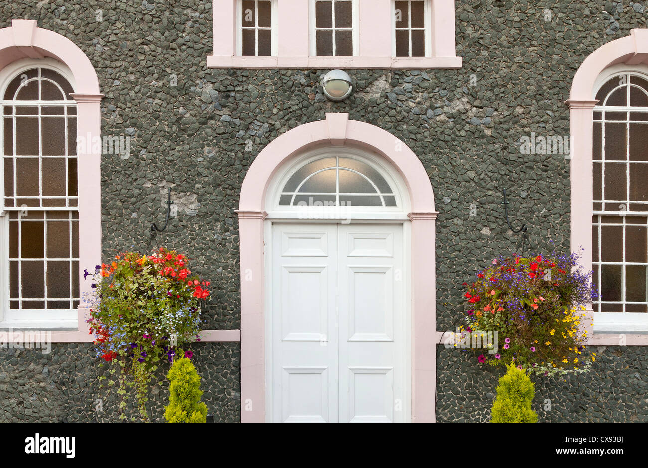 Blanc orné la porte de la chambre d'avant avec des fleurs paniers suspendus Banque D'Images