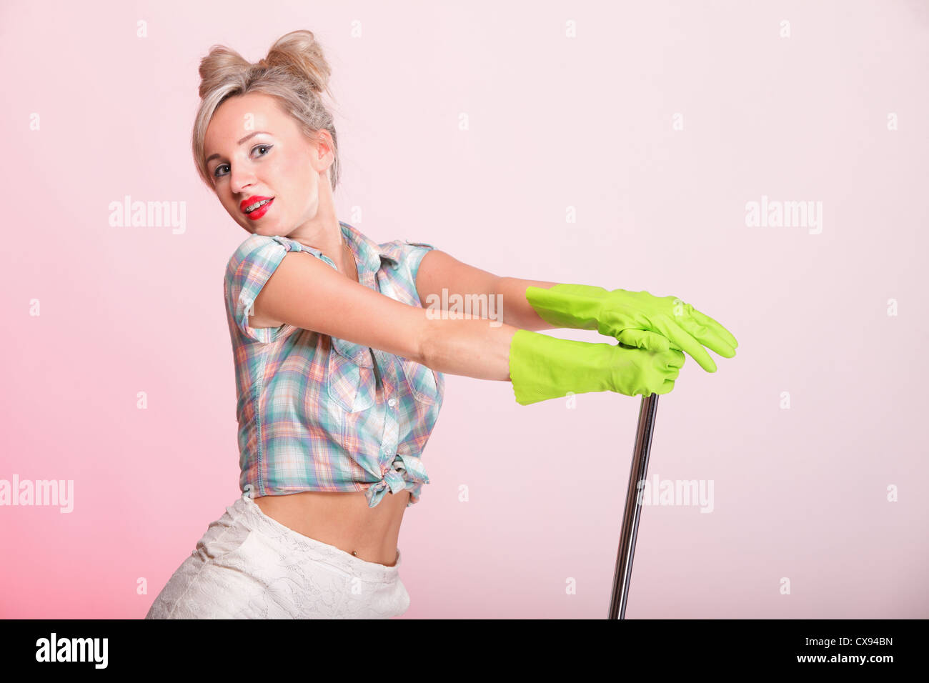Cheerful pin up girl portrait style rétro femme pinup housewife cleaner mop sur fond rose Banque D'Images