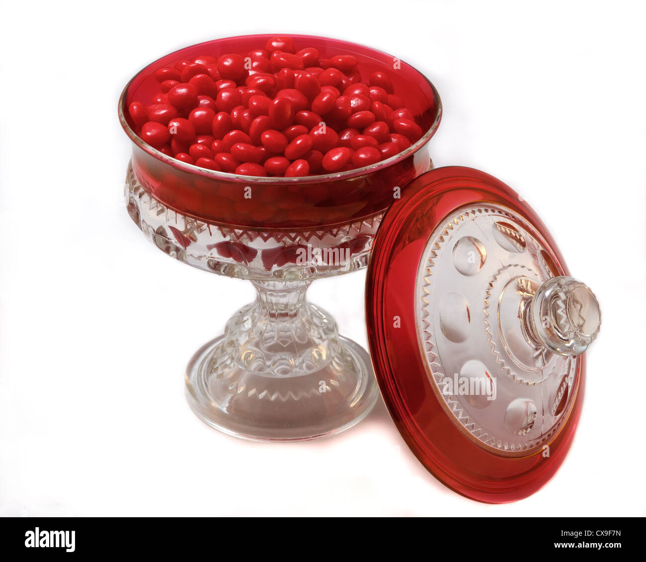 Bonbonnière en verre un caractère accentué en rouge et rempli de bonbons cannelle rouge. Banque D'Images