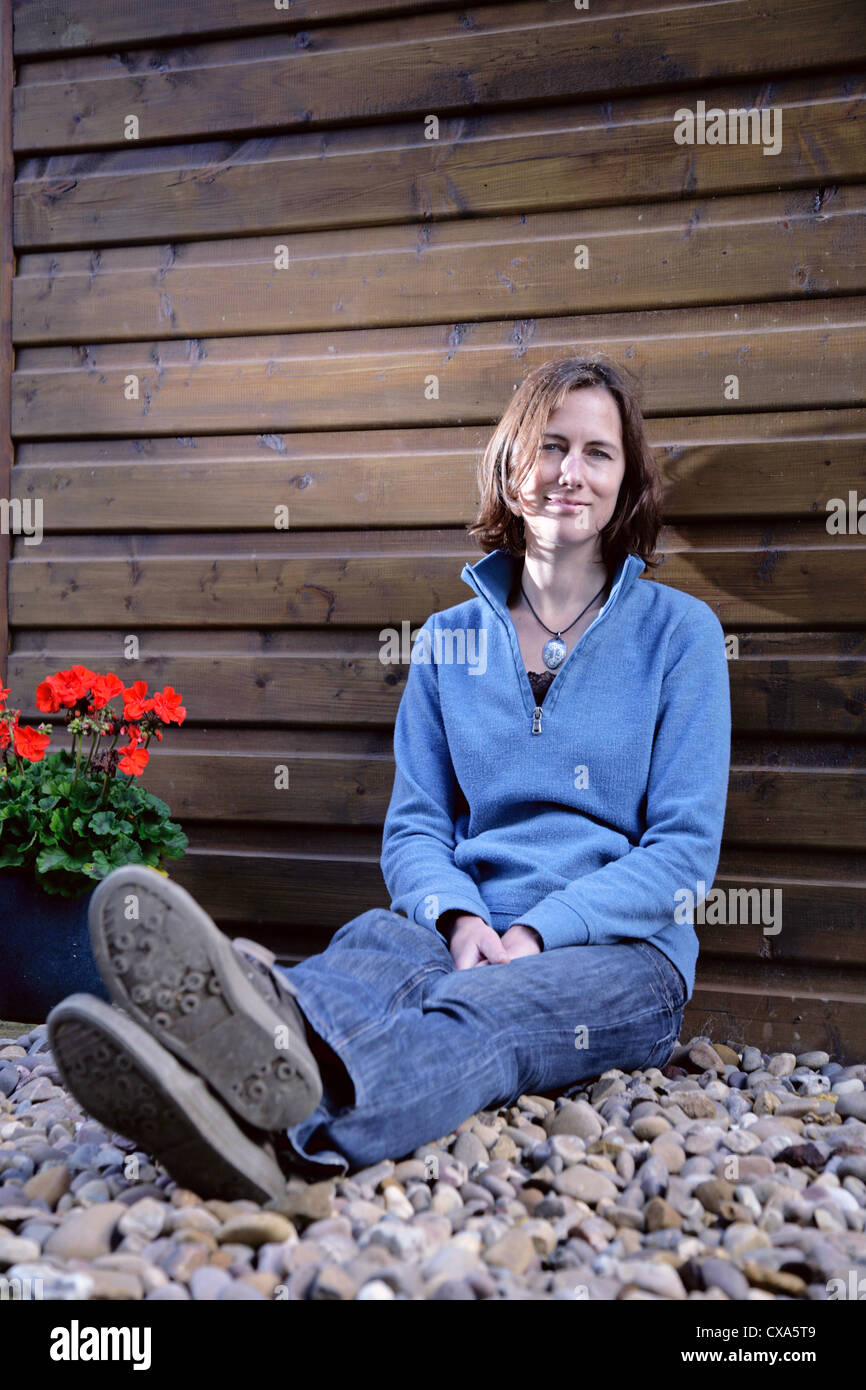 Happy young woman leaning against a wooden wall Banque D'Images