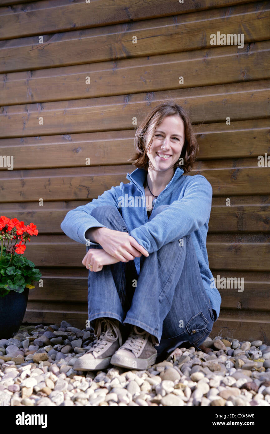 Happy young woman leaning against a wooden wall Banque D'Images