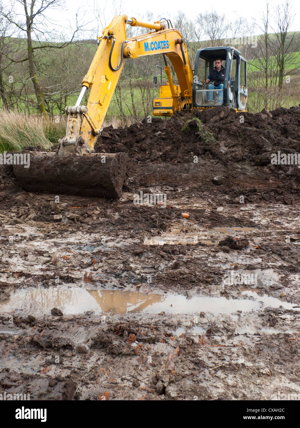 Entrepreneur avec une excavatrice 360degré creuser un étang de la faune dans une ferme. Powys, Pays de Galles. Avril Banque D'Images