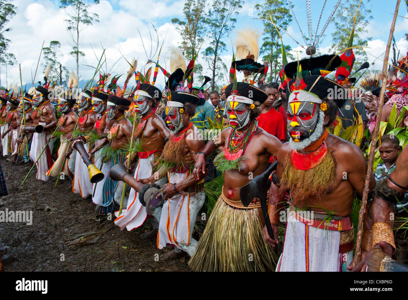 Habillés de couleurs vives et le visage peint les tribus locales pour célébrer la traditionnelle chanter chanter dans les hautes terres de Papouasie Nouvelle Guinée Banque D'Images