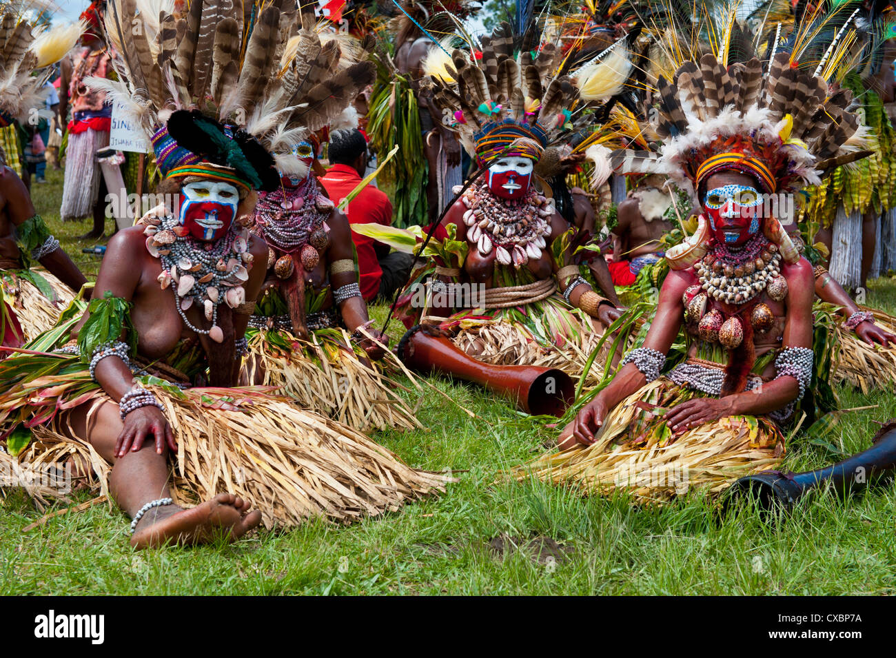 Habillés de couleurs vives et le visage peint les tribus locales pour célébrer la traditionnelle chanter chanter dans les hautes terres de Papouasie Nouvelle Guinée Banque D'Images