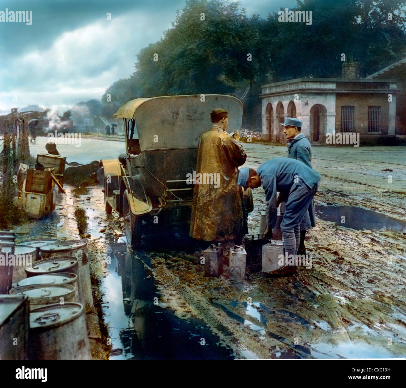 Photo colorisée des soldats français chargeant des réservoirs d'essence dans une automobile, arrêté sur une route boueuse, sur le chemin du front pendant la première Guerre mondiale, France, 1918. (Photo de Burton Holmes) Banque D'Images