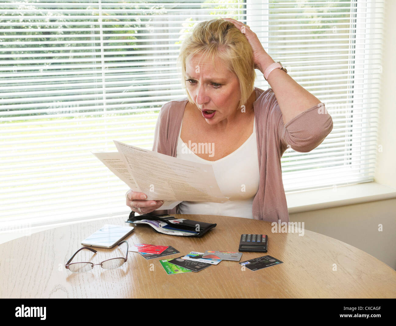 Femme choqué à la lecture de sa facture de carte de crédit Banque D'Images