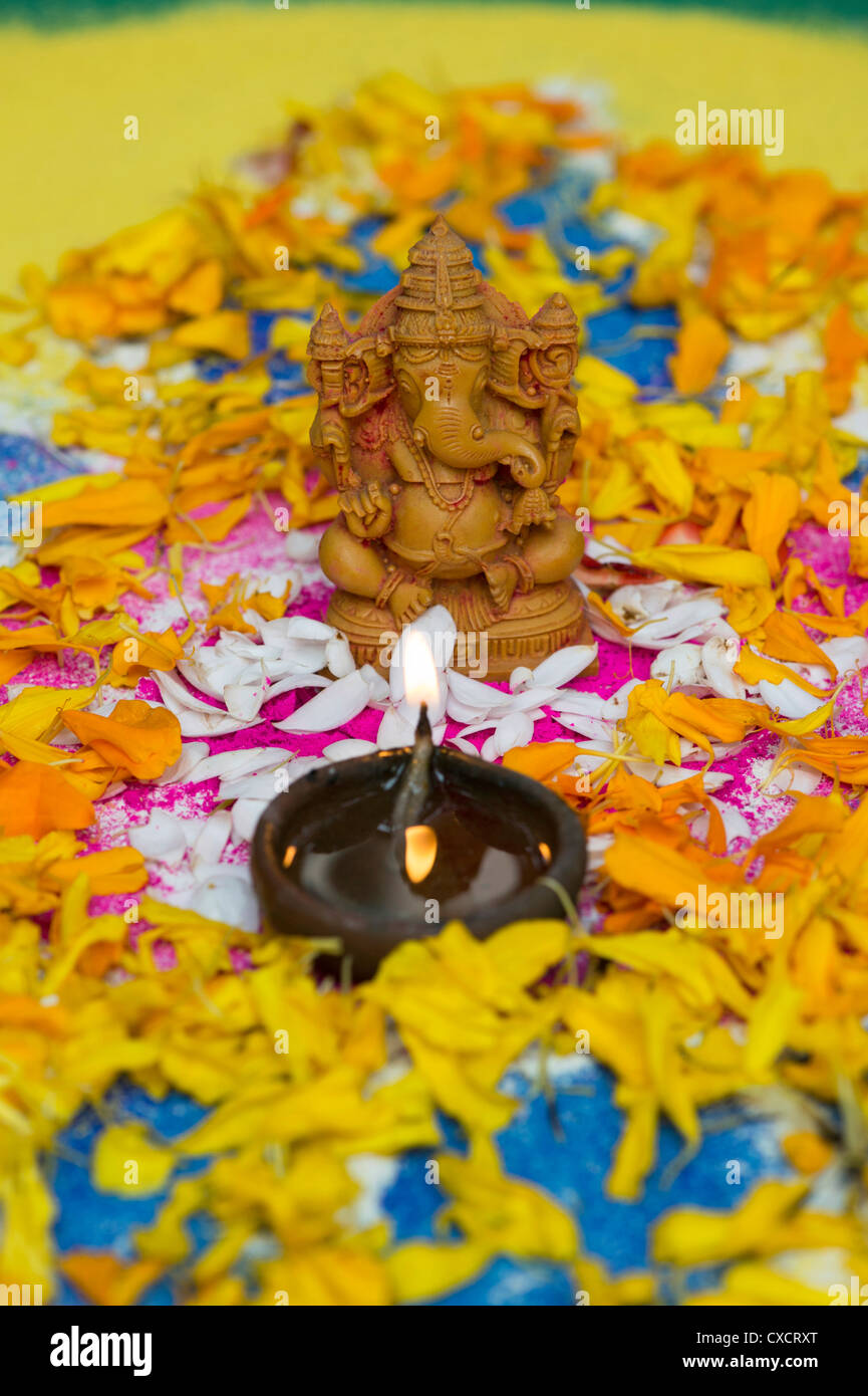 L'éléphant dieu hindou. Seigneur Ganesha statue avec lampe à pétrole et pétales de fleurs sur un Indien rangoli Banque D'Images