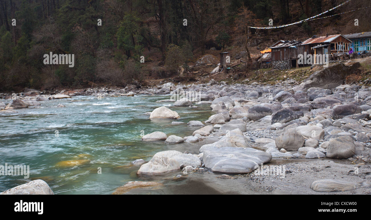 Femme assise à côté d'une rivière de montagne qui coule à travers la vallée du Langtang, au Népal Banque D'Images