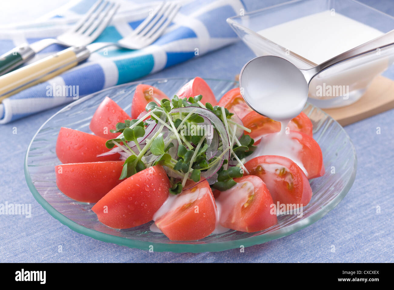 Verser la vinaigrette sur la salade de tomates Banque D'Images