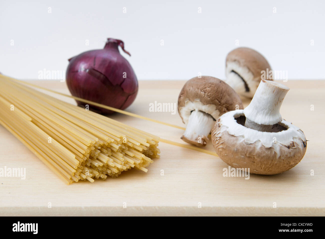 Les spaghettis, les champignons et l'oignon sur planche en bois en préparation pour la cuisson Banque D'Images
