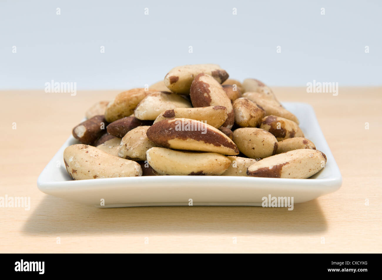 Les noix du Brésil écalées dans petit plat blanc sur planche en bois. Les noix du Brésil sont une riche source de sélénium Banque D'Images