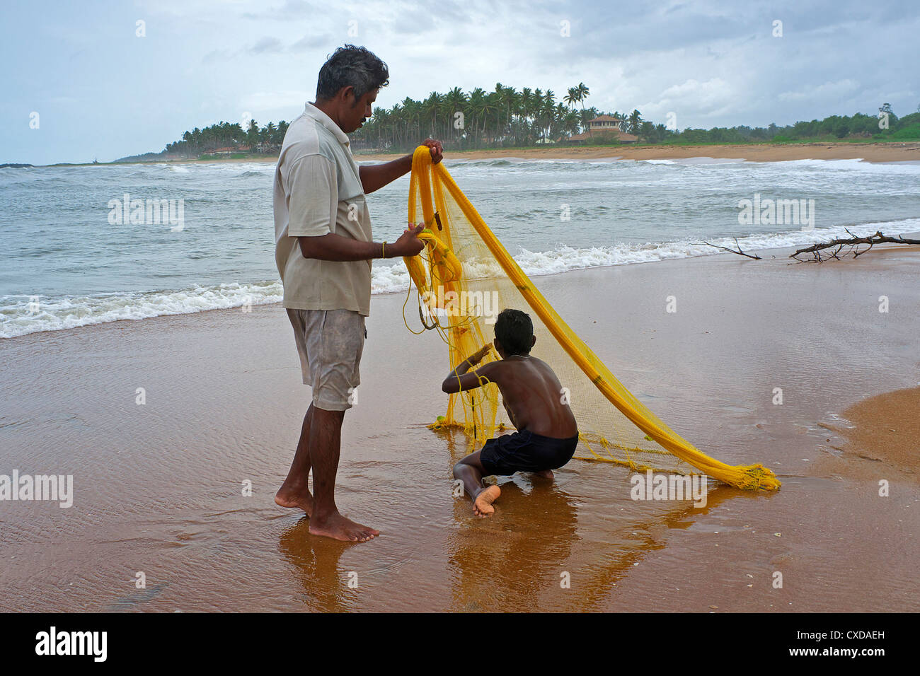 Père et fils à l'aide d'un filet de pêche lancer, près du village de Waikkal, Sri Lanka Banque D'Images