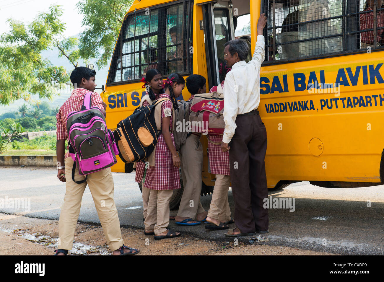 Les enfants de l'école indienne de monter dans un autobus scolaire étant encadré par un professeur. Puttaparthi, Andhra Pradesh, Inde Banque D'Images