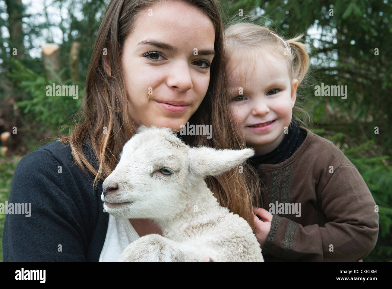Adolescente et sa petite sœur avec le pet lamb, portrait Banque D'Images