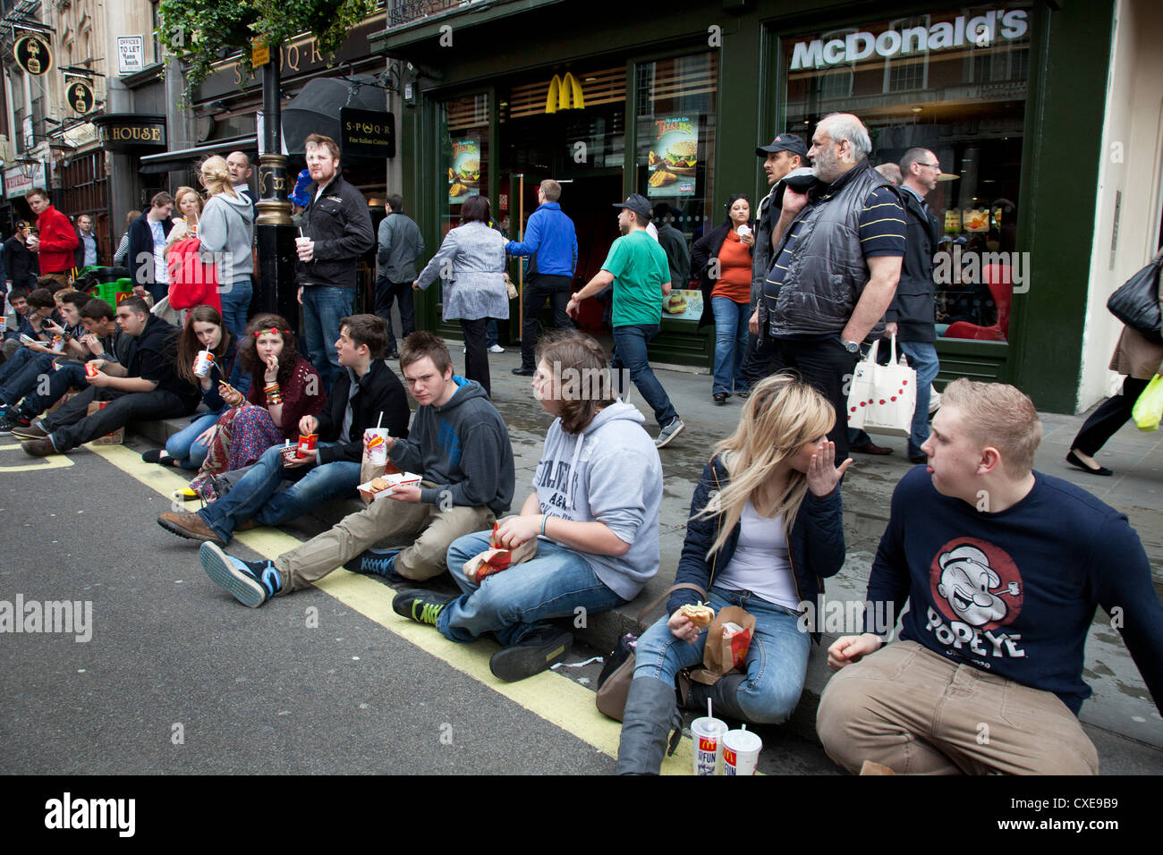 Les jeunes manger fast-food MCDONALD'S dans la rue à Londres. Banque D'Images