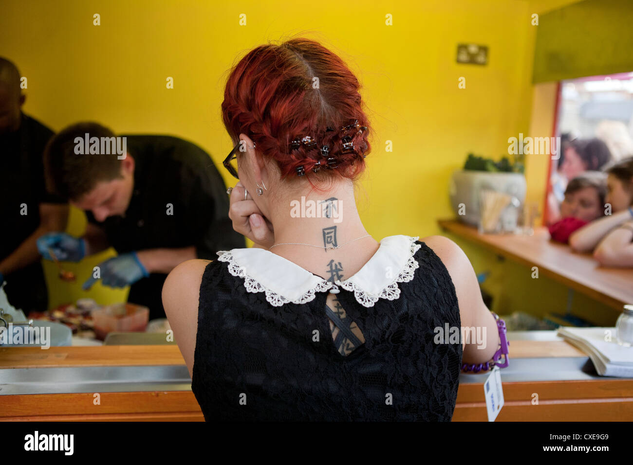 Londres, 22/08/2012, serveuse avec tatouage sur le cou est en attente de servir la nourriture dans un restaurant à Londres, Royaume-Uni Banque D'Images