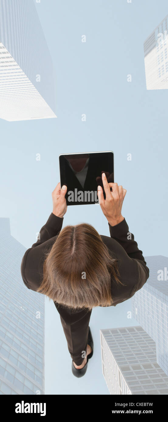 Businesswoman using digital tablet en marchant sur image superposée des gratte-ciel Banque D'Images
