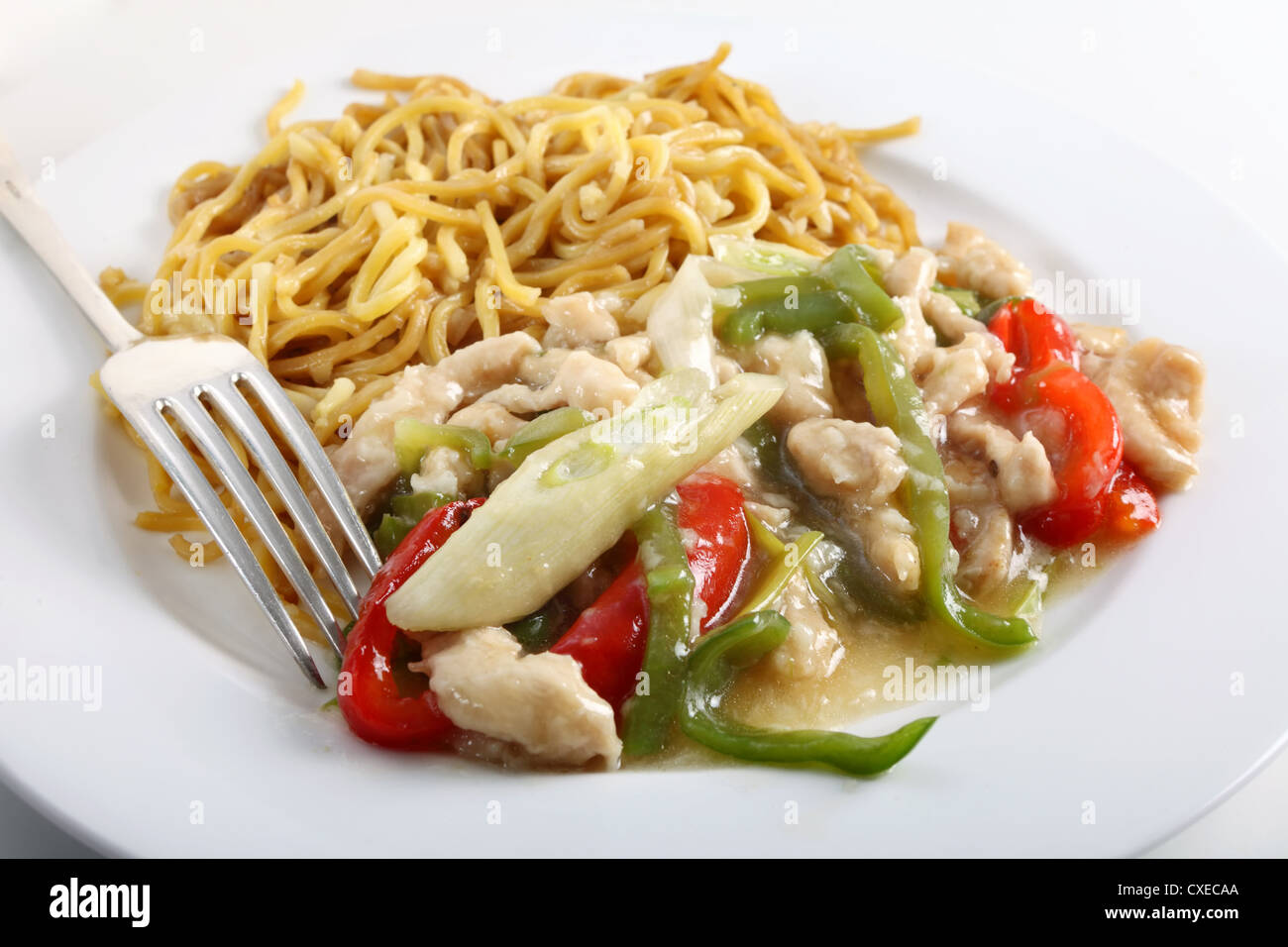 Un plat de poulet avec des poivrons verts et rouges, et chinois nouilles aux oeufs à la fourchette. Banque D'Images