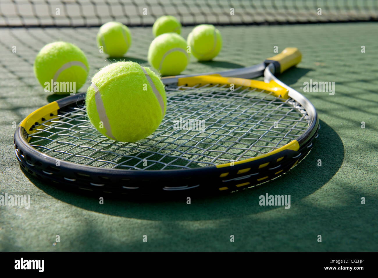 Un groupe de balles de tennis et une raquette de tennis sur un court de tennis en ciment fraîchement peint Banque D'Images