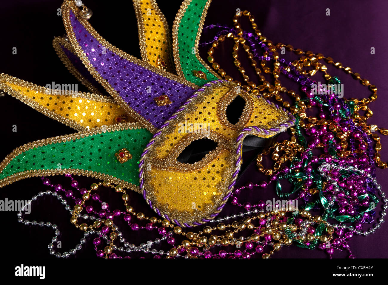 Un masque de bouffon Mardi Gras et des perles sur un fond noir Banque D'Images