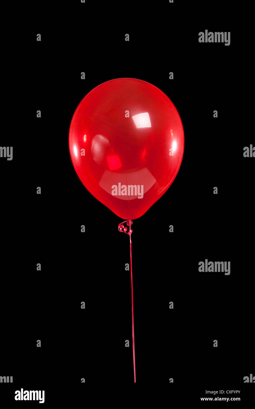 Seul ballon rouge sur fond noir Banque D'Images