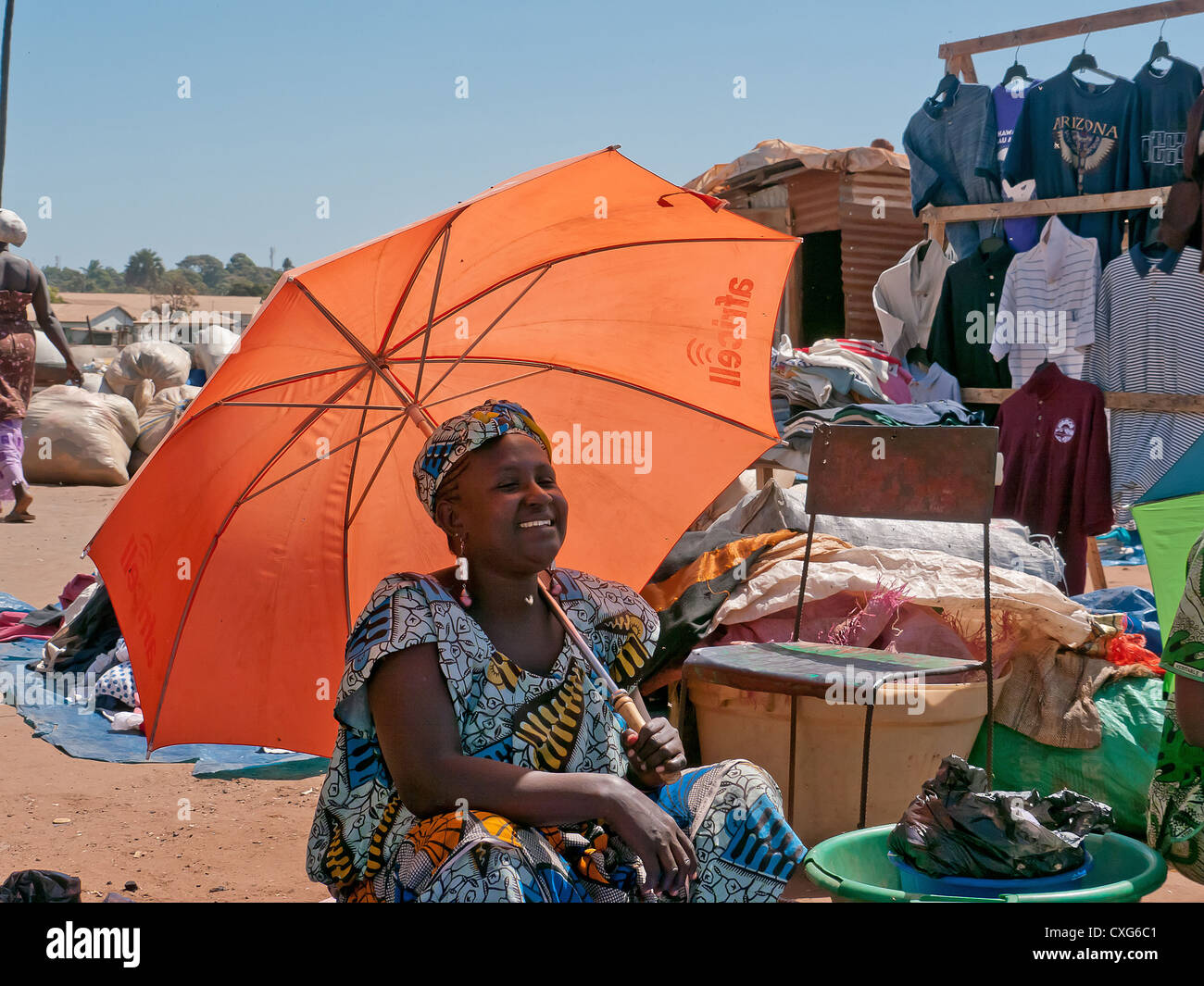 Femme gambienne sur orange parasol sur un marché en Afrique Gambie Photo  Stock - Alamy