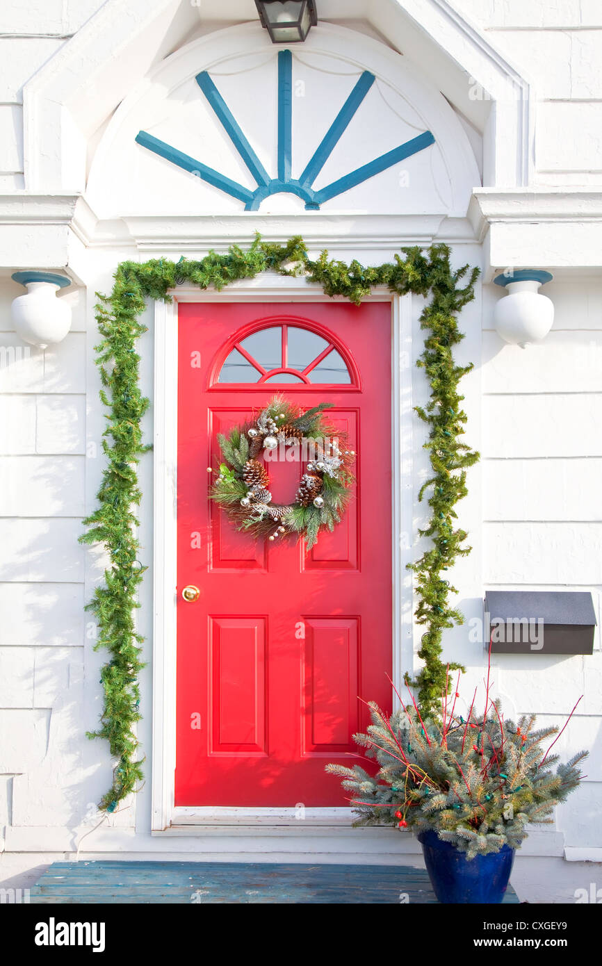 Couronne de Noël avec des babioles, cônes et branches de conifères sur une porte rouge. Banque D'Images