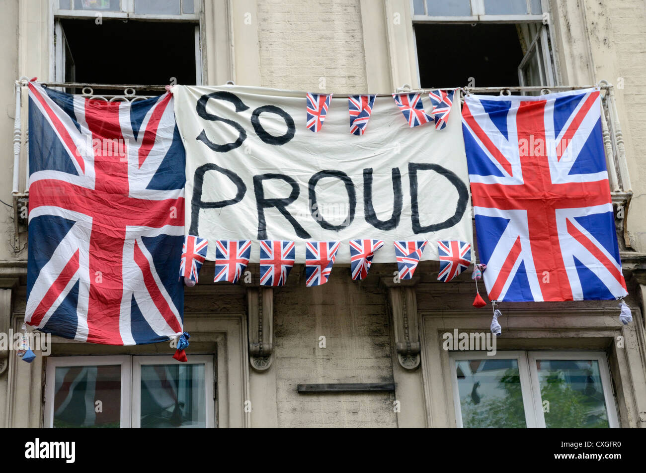 'Fier' bannière et Union Jack flags étendus dehors un immeuble de Londres pendant le défilé des athlètes à Londres en 2012. Banque D'Images