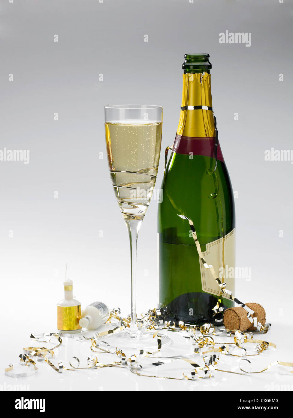 Une bouteille de champagne, verre de champagne, streamers et poppers sur un fond gris Banque D'Images