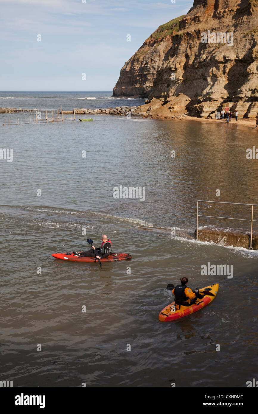 Deux personnes avec des kayaks à Staithes Harbour North Yorkshire UK Banque D'Images