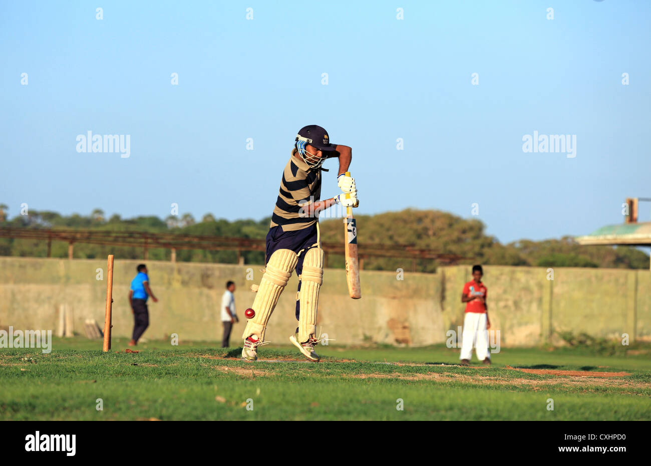 Les jeunes hommes jouant un jeu de cricket pratique à Trincomalee, Sri Lanka. Banque D'Images