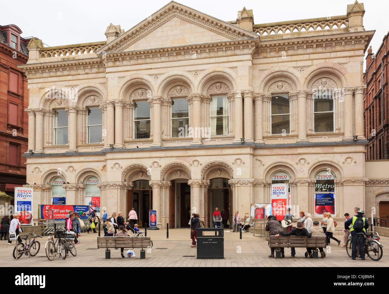 Scène de rue animée par Tesco Metro dans un immeuble ancien avec les consommateurs à l'extérieur dans le centre-ville de Belfast en Irlande du Nord UK Banque D'Images