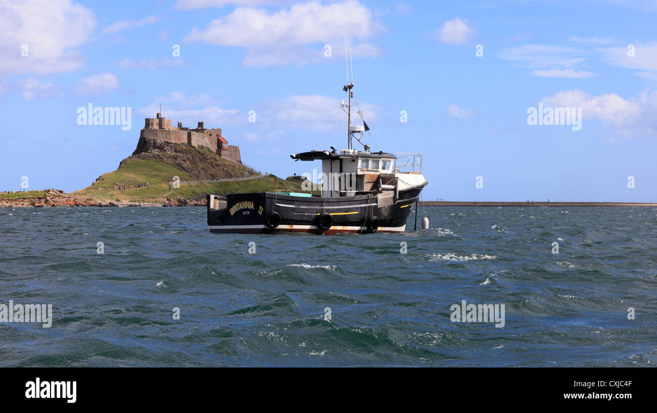 Château de Lindisfarne, Holy Island, de la mer, avec un bateau au premier plan. Banque D'Images