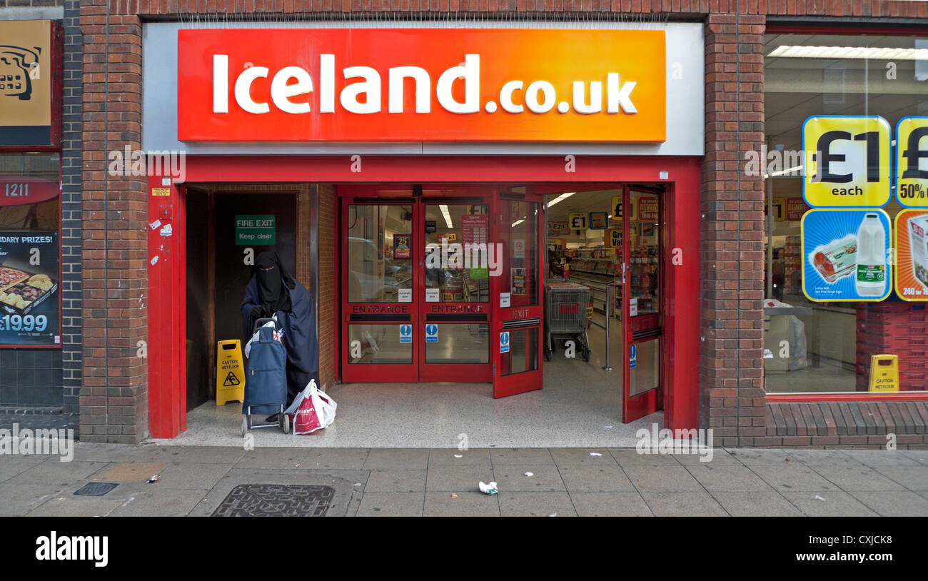 Une femme musulmane dans une burka avec panier debout à l'extérieur du magasin Islande Walthamstow High Street London England UK KATHY DEWITT Banque D'Images