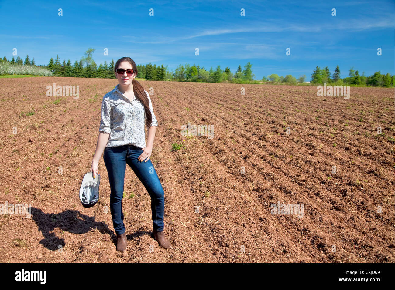 Jeune femme agriculteur debout devant un champ nouvellement semées. Banque D'Images