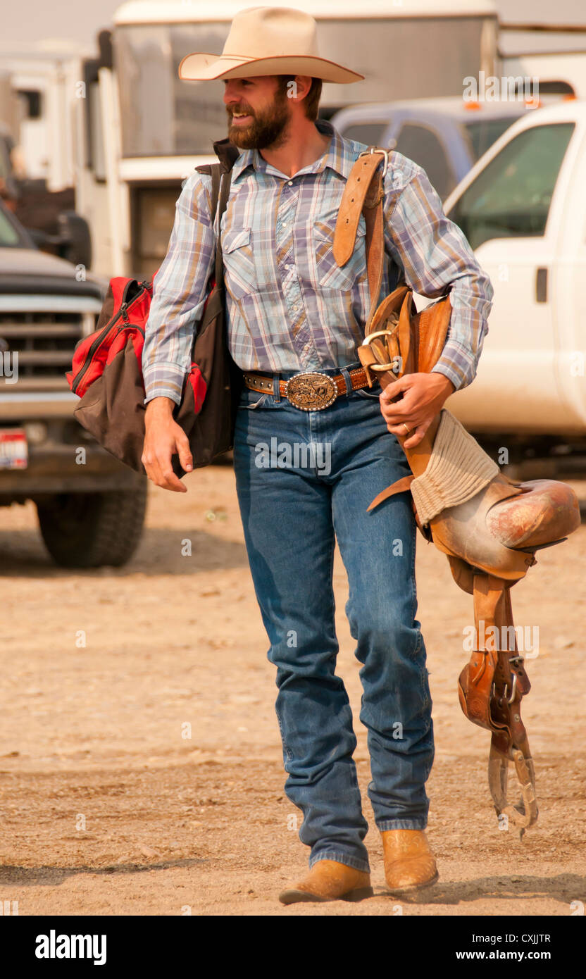 Cowboy bronc rider portant sa selle pour l'arène de rodéo, Bruneau, California, USA Banque D'Images