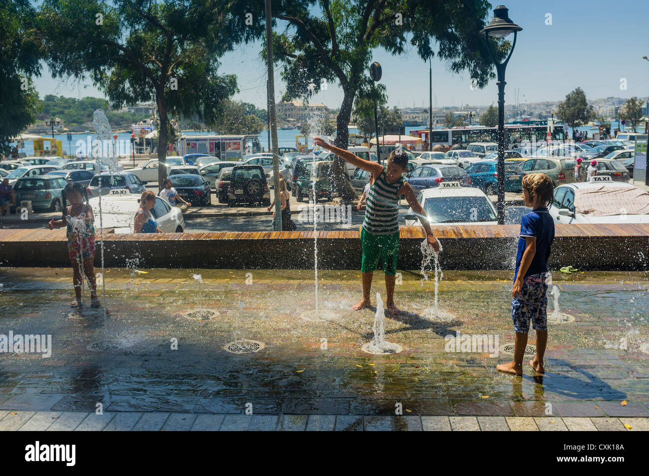 Trois enfants qui jouent dans une fontaine ornementale dans la ville de Sliema à Malte Banque D'Images