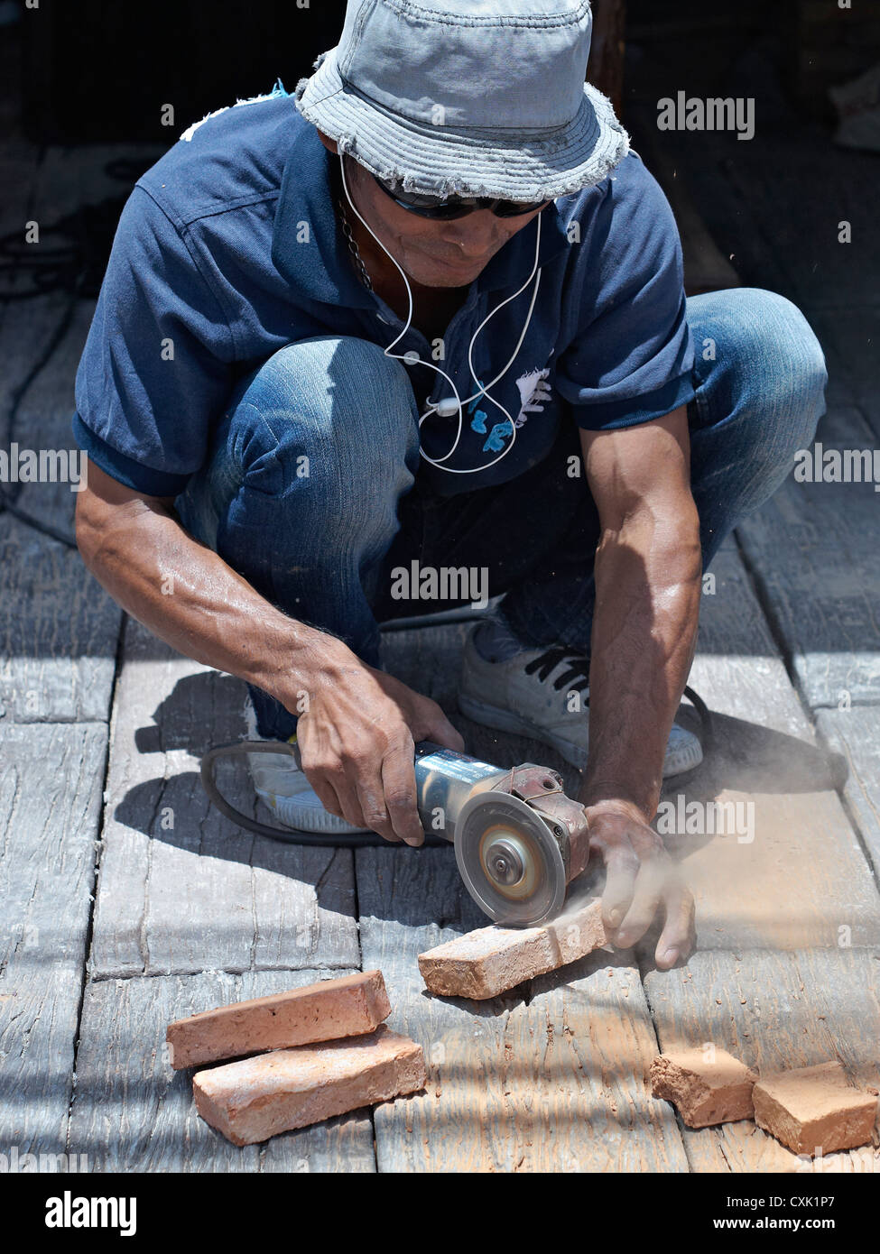 Meuleuse d'angle. Constructeur utilisant une meuleuse d'angle manuelle pour couper des briques. Thaïlande S.E. Asie Banque D'Images