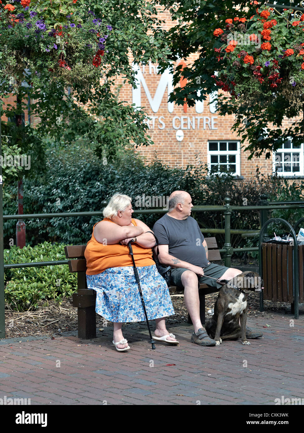 Une femme en surpoids s'est assise avec son mari et son chien de compagnie et s'est assise sur le banc du parc. Angleterre Royaume-Uni Banque D'Images